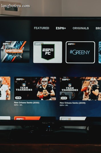 A television screen displaying the ESPN+ streaming interface with various sports-related shows and categories. The screen includes sections such as 'Browse by Shows' and 'Best of Drew Brees' with thumbnails of sports programs featuring athletes in action and analysts.